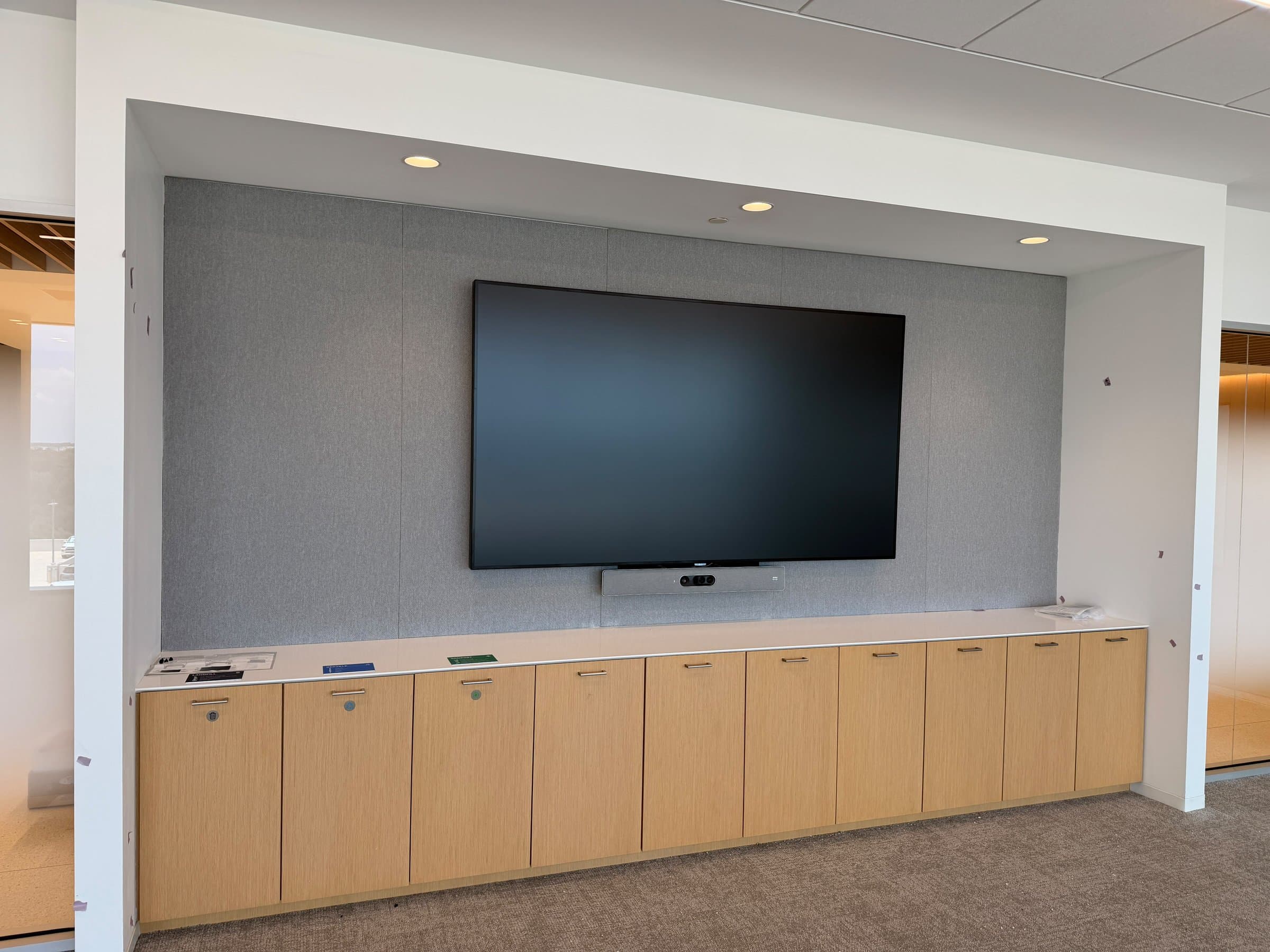 Executive boardroom display recessed into an acoustic-fabric niche above a millwork credenza