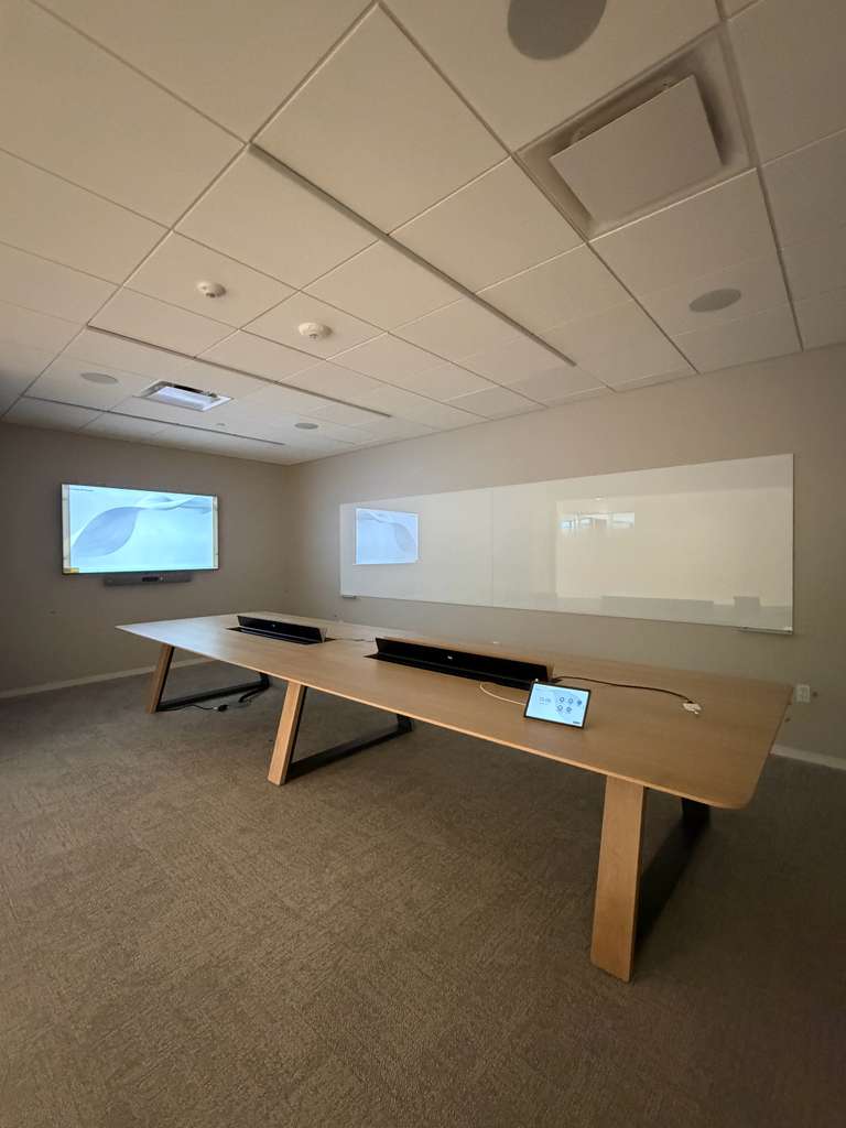 Meeting room display facing a full-wall glass whiteboard, with retractable table boxes for power and data