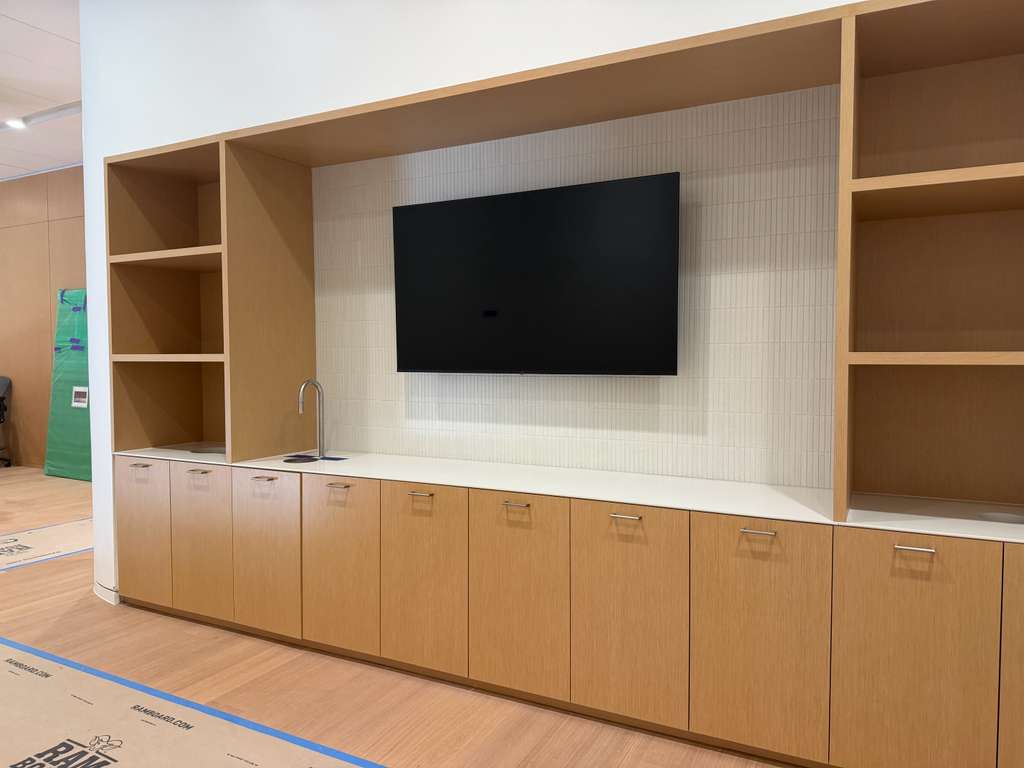 Break area display set into custom millwork above the counter and sink, on a tiled feature wall with no visible cabling