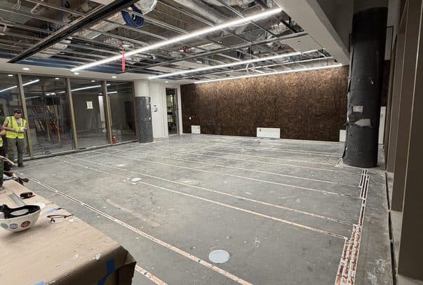 Open-ceiling commercial floor during rough-in, with cable runs taped across the slab