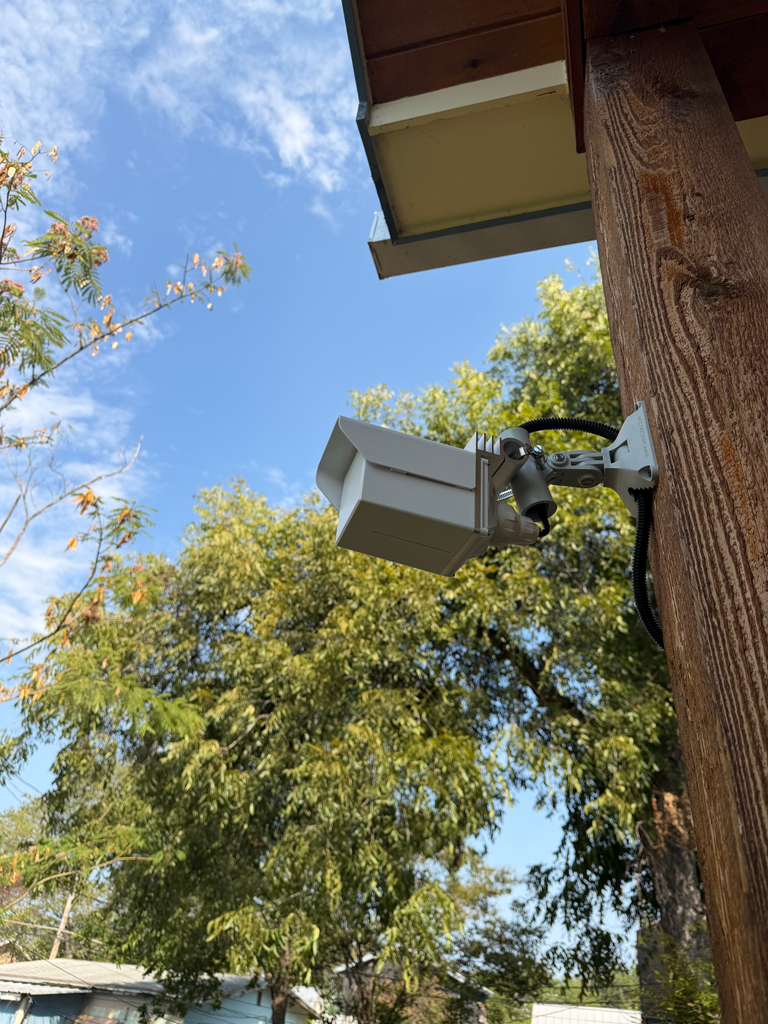 Close view of an outdoor point-to-point bridge aligned on its adjustable mount, shielded under the eave