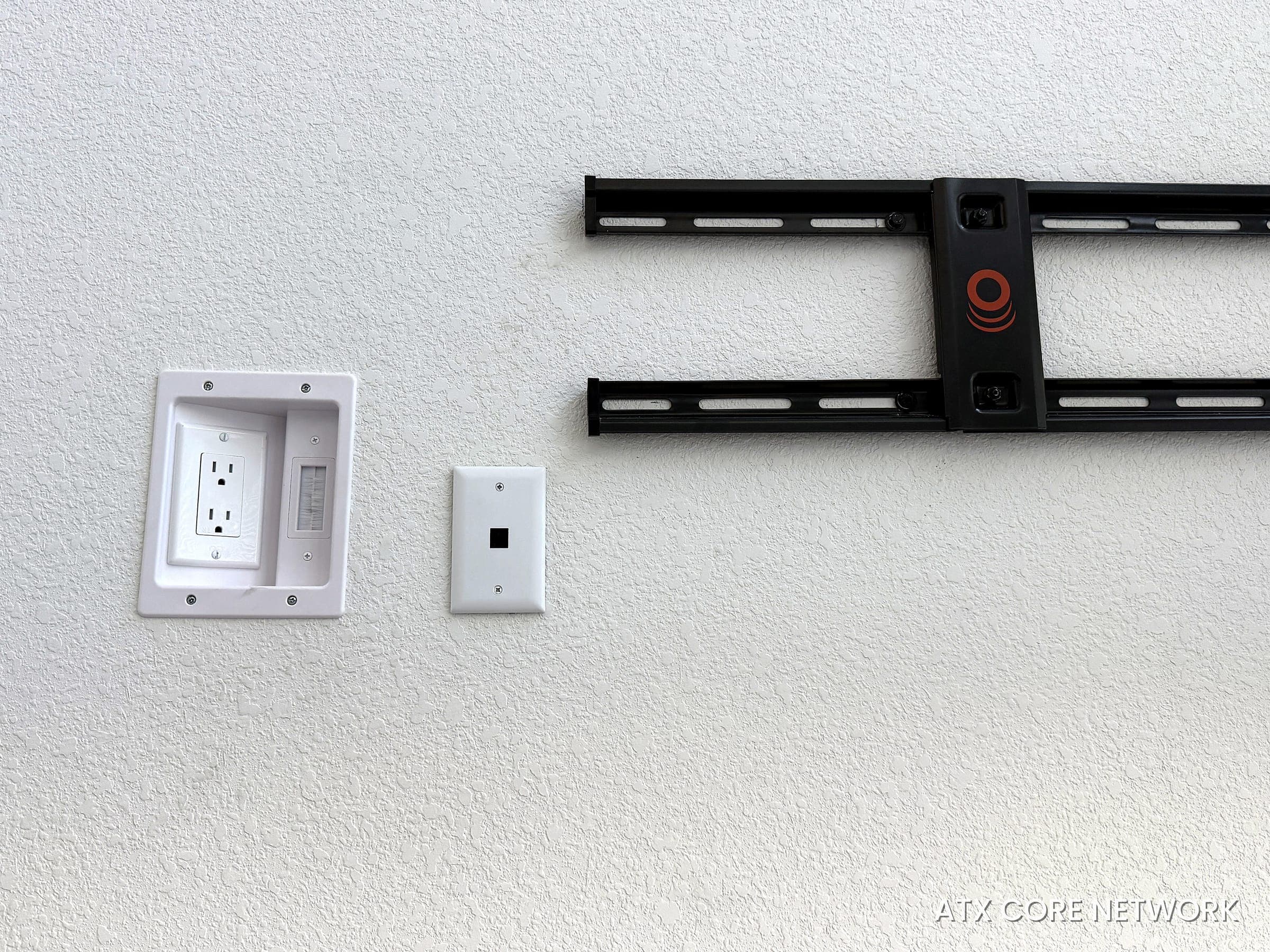 In-wall TV prep — recessed power, data jack and mount rails, no visible cables