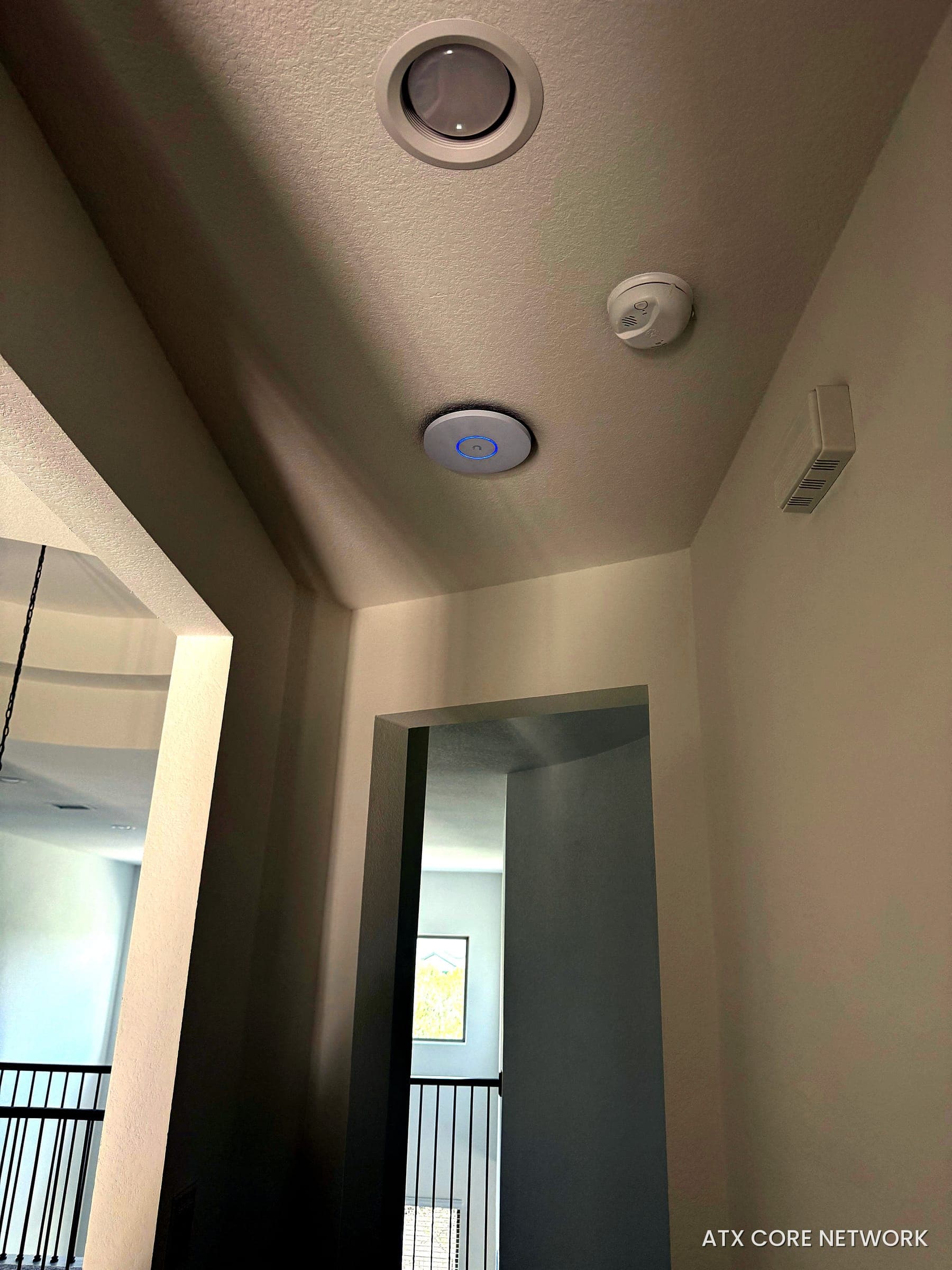 Hallway ceiling Wi-Fi access point blended in beside home safety devices