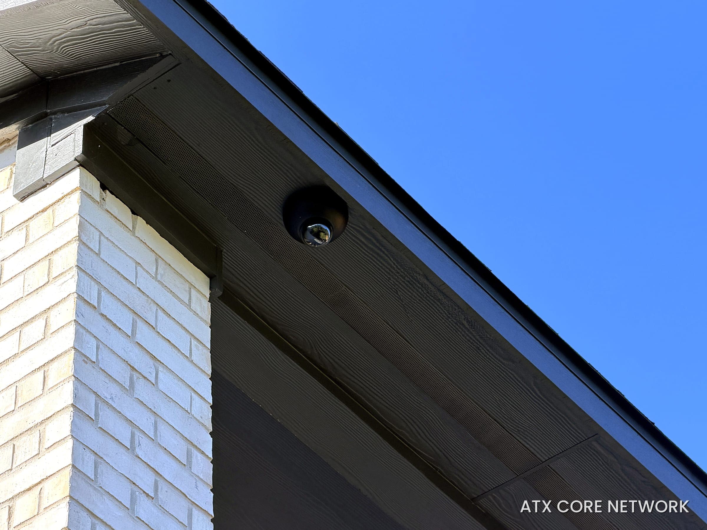 Low-profile black dome camera tucked into a dark modern soffit